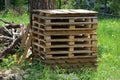 A row of brown wooden pallets standing in green grass by a tree