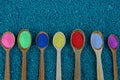 A row of wooden spoons with colored powder on blue stones Royalty Free Stock Photo