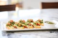 row of bruschetta on a ceramic platter with a small bowl of pesto sauce beside Royalty Free Stock Photo