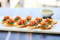 row of bruschetta on a ceramic platter with a small bowl of pesto sauce beside Royalty Free Stock Photo