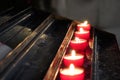 A row of burning tea light candles in church with focus on the middle one. Royalty Free Stock Photo