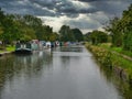 A row of canal narrowboats moored at permanent moorings in Halsall in Lancashire, taken on a grey, rainy day in summer