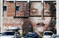 Row of cars parked in front of a mural of a female on a brick wall in Christchurch, New Zealand