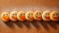A row of cheerful smiley-faced jam-filled cookies dusted with powdered sugar casting soft shadows on a rustic brown textured Royalty Free Stock Photo