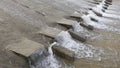 Row of chute dentate blocks in concrete water spillway channel slope slowing down the flow of water running down