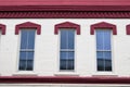 Row of city building windows with painted cream brick and red trim