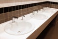 Row of clean ceramic sinks in public toilet Royalty Free Stock Photo