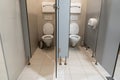 Row of clean toilet cubicles with open door in a public restroom