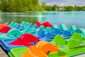 The row of colored plastic catamarans near a wooden pier with lake and forest on the background