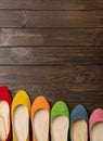 Row of colored shoes ballerinas on a dark wooden background. Royalty Free Stock Photo