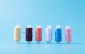 In a row colored spools of sewing thread on a blue background. fighting squad with a needle Royalty Free Stock Photo