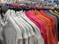 Row of colorful Apparel on Shoulders Hangers of T-Shirts of Retail Shop with other Items on Background, interior of cloth store Royalty Free Stock Photo