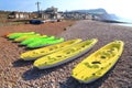 Row Of Colorful Kayaks On A Pebble Beach