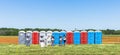 Row of colorful mobility lavatory and washbasin, hygiene facility for people at outdoor event. Public temporary restroom at a park