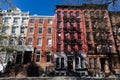 Row of Colorful Old Brick Apartment Buildings with Fire Escapes in the East Village of New York City along a Street and Sidewalk