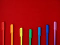 The row of colorful rainbow pens lying on bright red paper background in form of smile. Horizontal, copy space Royalty Free Stock Photo