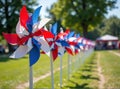 Row of colorful red, white, and blue pinwheels on a sunny day in a park setting Royalty Free Stock Photo