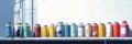 A row of colorful spray paint cans on a shelf with a window in the background Royalty Free Stock Photo