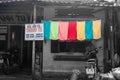 Row of colorful towels drying outdoors on street in monochrome image