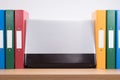 Row of coloured office folders and computer laptop Royalty Free Stock Photo