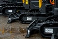 Row of compact excavators with rubber crawler tracks and hydraulic dozer blades aligned on wet construction surface showing Royalty Free Stock Photo