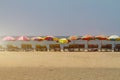Row of covered wooden deck chairs with colorful umbrellas