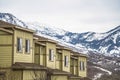 Row of cream colored homes with snow covered mountain and cloudy sky background Royalty Free Stock Photo