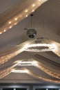 Row of crystal light rings and swags of lights in tulle with silver disco ball hanging from white ceiling Royalty Free Stock Photo