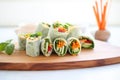 row of cucumber and bell pepper wraps on a wooden platter