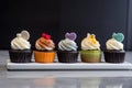 row of cupcakes, each topped with unique and unexpected flavor combination