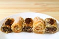 Row of delectable Baklava sweets on a white plate served on wooden table
