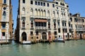 A row of different houses on the waterfront with a pier and boats in Venice, Italy. View against the background of the blue sky