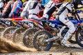 Row of dirt bike racers speeding through dirt track in daylight Royalty Free Stock Photo