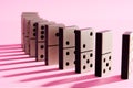 Row of domino tiles on pink studio background close up Royalty Free Stock Photo