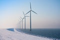 Row of Dutch windmills disappearing in winter haze