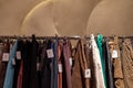 Row of earth tone colour fabric jeans or denim trousers and slacks hang on hanger.