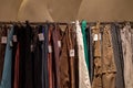 Row of earth tone colour fabric jeans or denim trousers and slacks hang on hanger.
