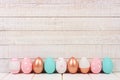 Row of Easter eggs on white wood. Rose gold, pink, turquoise and white. Royalty Free Stock Photo