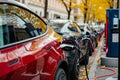 Row of electric cars at public charging station with plugged power cables Royalty Free Stock Photo