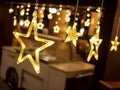 Row of electric lighted stars with warm yellow lights in a against a dark backdrop. Festive / holiday mood concept