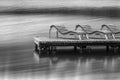 Row of empty deck chairs on dock at lake. Wooden bridge with sun-beds and observation space