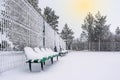 The row of empty plastic green seats at sports ground covered with snow