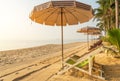 Row of empty wooden beach chairs with parasols on tropical sandy beach in the morning Royalty Free Stock Photo