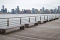 Row of Empty Wood Benches on a Pier along the Hudson River with the Jersey City Skyline in the Background in New York City Royalty Free Stock Photo