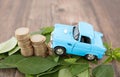 A row of euro coins surrounded by fresh green leaves and cars climbing on them