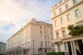 Row of facades of beige stone buildings under blue cloudy sky in Kensington, London