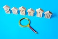 A row of figures of houses and a magnifying glass. The concept of finding an apartment for rent or purchase. Buying or renting