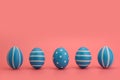 A row of five blue decorated Easter eggs on a pink background. Royalty Free Stock Photo