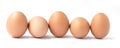 Row of five brown chicken eggs.