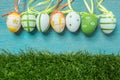 A row of five colorful easter eggs on blue Background and grass Royalty Free Stock Photo
